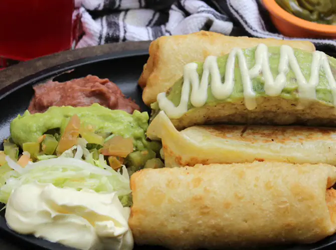 Flautas con guacamole, frijol refrito, lechuga y sour cream